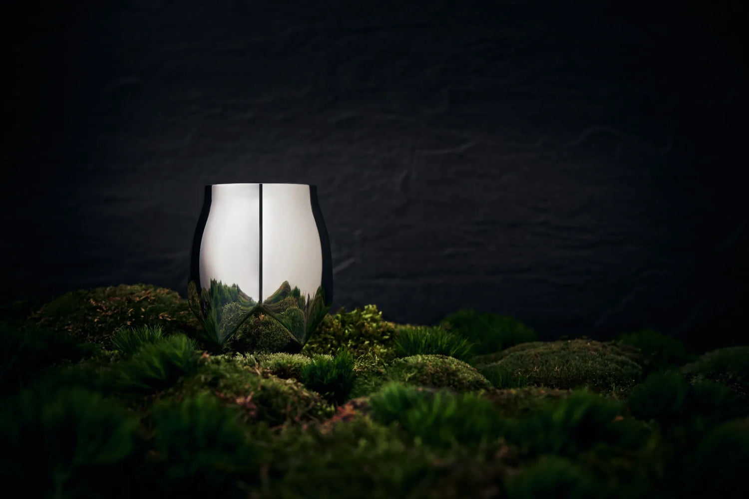 Norlan Steel Tumbler in polished steel sitting on a bed of lush green moss with a stone backdrop.